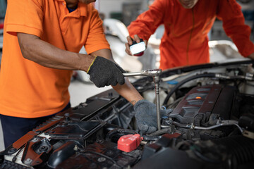 Asia mechanic man examining and maintenance to engine a vehicle car hood with car lift background at car service