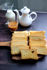 Tea Time Snack. Healthy Wheat rusk served with Indian hot masala tea and milk jug over black background. also known as Mumbai cutting chai. with Copy space. Crunchy rusk or toast.