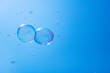 Soap bubbles in the blue sky. Beautifully iridescent balls of soap foam in the air