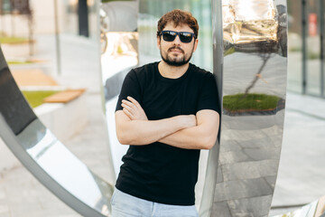 Young stylish bearded man  in a black T-shirt and sunglasses. Street photo