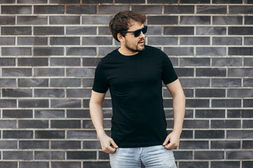 Young stylish bearded man  in a black T-shirt and sunglasses. Street photo