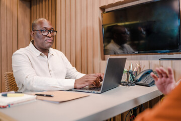 Latin black man bank manager in Brazil using computer to do credit analysis of his clients who are applying for bank loan