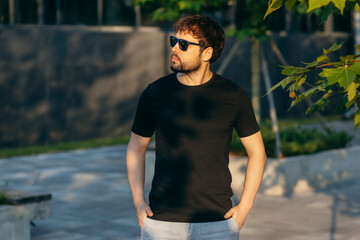 Young stylish bearded man  in a black T-shirt and sunglasses. Street photo