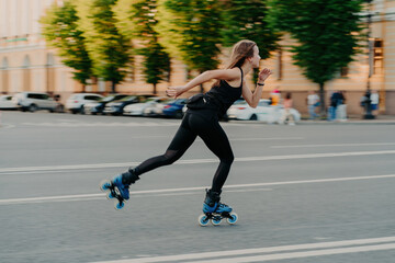 Professional female roller demonstrates her abilities of rollerblading rides very quckly on road...