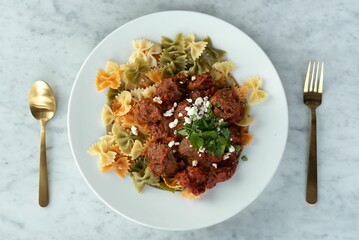 a plate of pasta with meat and spices on it and a spoon next to it