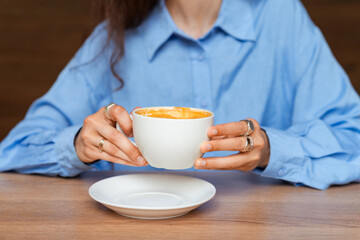 Stylish woman in blue shirt holding cup with coffee. Coffee break concept