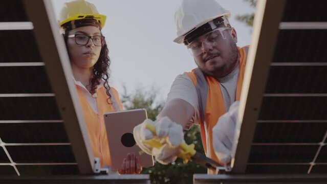 tecnicos vestindo equipamentos de protecao instalando paineis de energia fotovoltaica em uma propriedade rural na America Latina