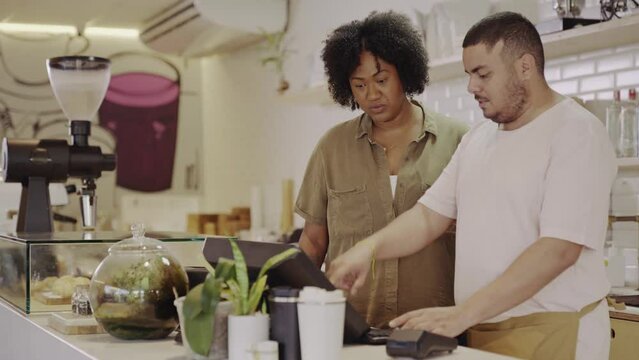 novo funcionario recebendo treinamento da gerente usando o computador em uma cafeteria no Brasil