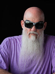 Portrait of man with long gray beard wearing purple t-shirt and sunglasses close-up shot