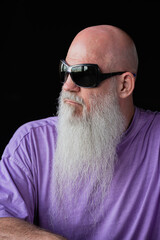 Portrait of man with long gray beard wearing purple t-shirt and sunglasses close-up shot