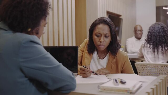 Brazilian woman customer of a bank in Brazil smiling while signing the bank loan agreement and shaking the manager's hand