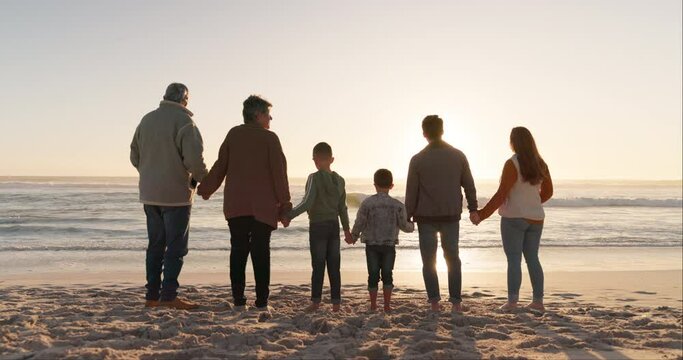 Family holding hands, ocean and beach with back view, grandparents and parents with children at sunrise and travel. Love, care and support, vacation and solidarity, women and men with kids outdoor