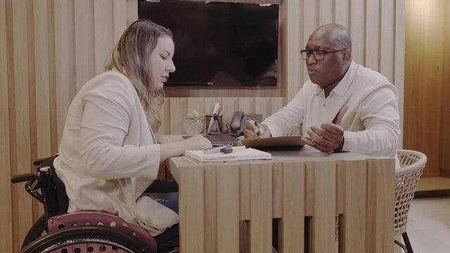 Brazilian woman in a wheelchair financial analyst at a bank in Brazil explaining the terms of her bank loan agreement to a customer