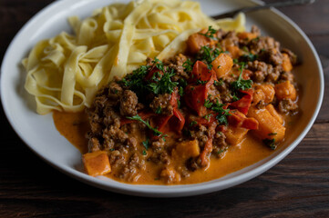 Pasta with ground beef, sweet potatoes and vegetables in a delicious cream sauce on a plate