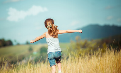 little girl runs through a beautiful meadow in the mountains. back view