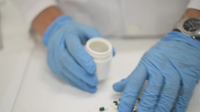 Male pharmacist filling jar with capsules in lab
