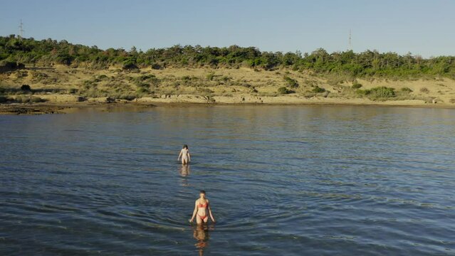 Two young women are walking in the shallow sea in Rab Island, Croatia