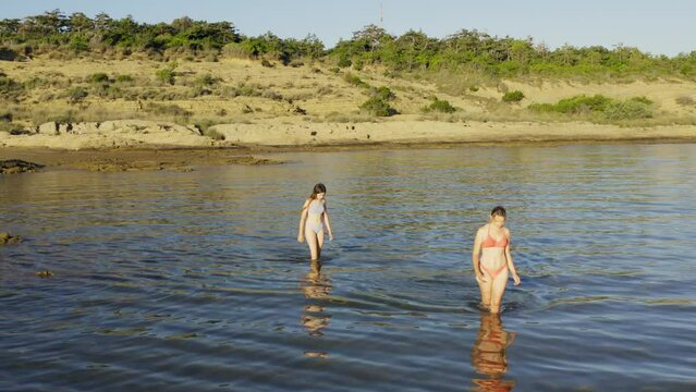 Two young women are walking in the shallow sea in Rab Island, Croatia