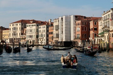 Fototapeta na wymiar Group of people in small vessels navigating through a canal in Venice