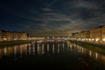Tranquil scene featuring a a bridge over the tranquil river in Florence, Italy at night