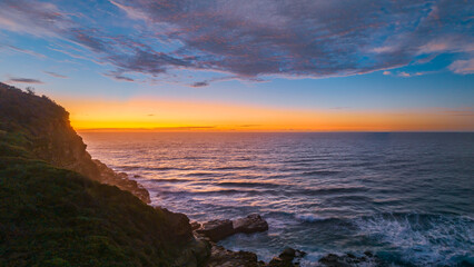 Fototapeta premium Ocean sunrise panorama with headland and clouds