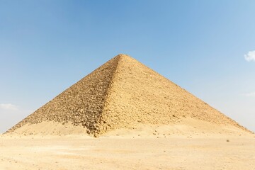 a large pyramid with sand covering it in the desert against a blue sky