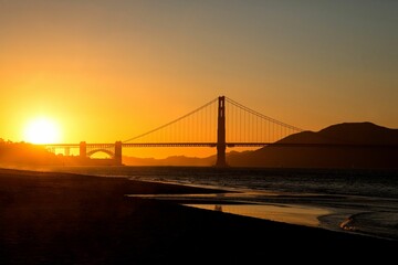 Stunning shot of a sun-drenched bridge and bay, with a brilliant orange sky in the background
