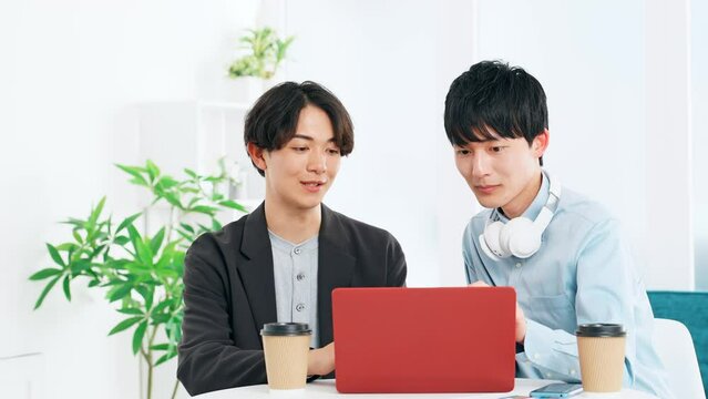ノートパソコンを見る二人の若い男性