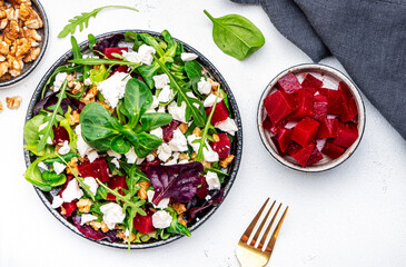 Beetroot and white cheese salad with arugula, lettuce, chard and walnuts, white table, copy space....