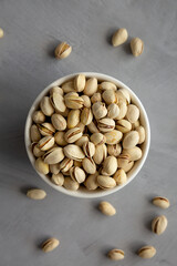 Salted and Roasted Pistachios in a Bowl on a gray background, top view. Overhead, from above, flat lay.