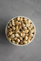Salted and Roasted Pistachios in a Bowl on a gray background, top view. Overhead, from above, flat lay.