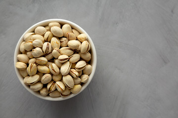 Salted and Roasted Pistachios in a Bowl on a gray background, top view. Overhead, from above, flat lay. Copy space.