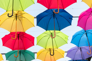 Lots of umbrellas coloring the sky in the city,Colorful yellow red blue white green pink color fabric umbrella with blue sky cloud background