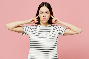 Young sad caucasian woman she wears casual clothes t-shirt cover ears with hands fingers do not want to listen scream isolated on plain pastel light pink background studio portrait. Lifestyle concept.