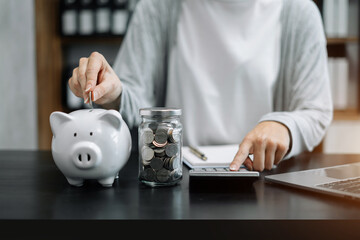 Woman sitting at desk managing expenses, calculating expenses, paying bills using laptop online,...