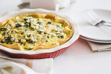 Quiche. Healthy homemade chicken pie with broccoli and spinach on white wooden table
