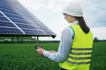 Portrait of a technical engineer with a tablet in his hands, standing in front of an unfinished tall outdoor solar panel of a photovoltaic system, technical engineer girl