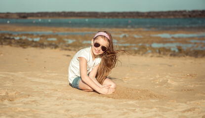 Fototapeta premium little girl in a hat on a sandy beach