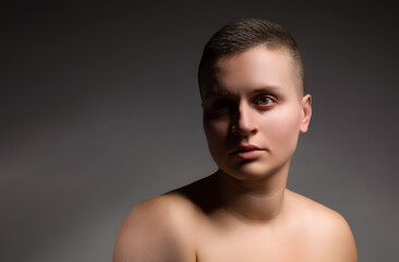 portrait of young woman with short hair and bare shoulder on grey background