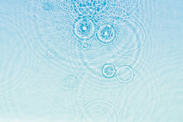 abstract fresh transparent blue water surface from above with rain drop circles in sunlight, liquid...