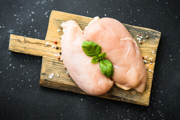 Chicken fillet, raw chicken meat breast with herbs and spices at dark background. Top view with...