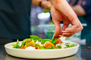 chef hand decorated smoked salmon salad with cucumbers, cream cheese, arugula