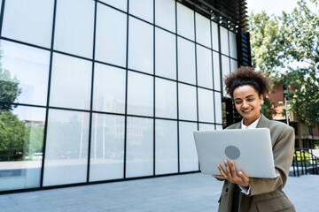 Portrait of professional female financial lawyer standing in front of an office on street communicating online using tablet, business woman pushes message to colleagues using a touch pane