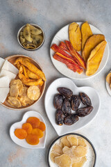 Assorted exotic dried fruits on plates on a white background. Dried mango, papaya, pineapple,...