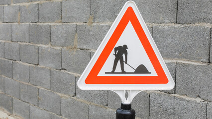 Grey brick wall and road sign with road works close up texture background	
