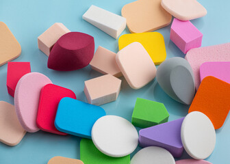 Heap of colorful cosmetic sponges on blue background. Top view