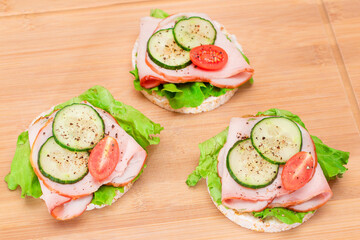 Light Breakfast. Quick and Healthy Sandwiches. Rice Cakes with Ham, Tomato, Fresh Cucumber and Green Salad on Wooden Cutting Board