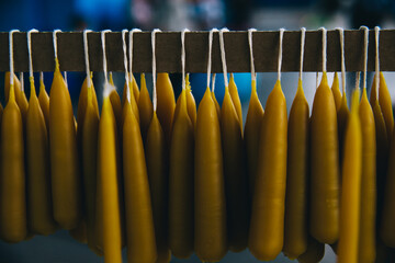 Wax conical (table) candles made of beeswax hang on ropes