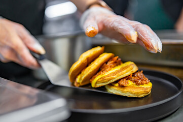 woman chef hand cooking pancakes with meat, bacon and cheese sauce