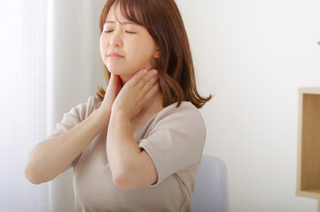 首のまわりが痛そうな若い女性